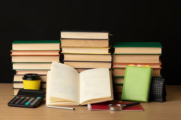 A stack of books alongside a notebook and a calculator