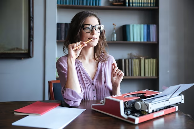 Woman contemplating in front of a typewriter