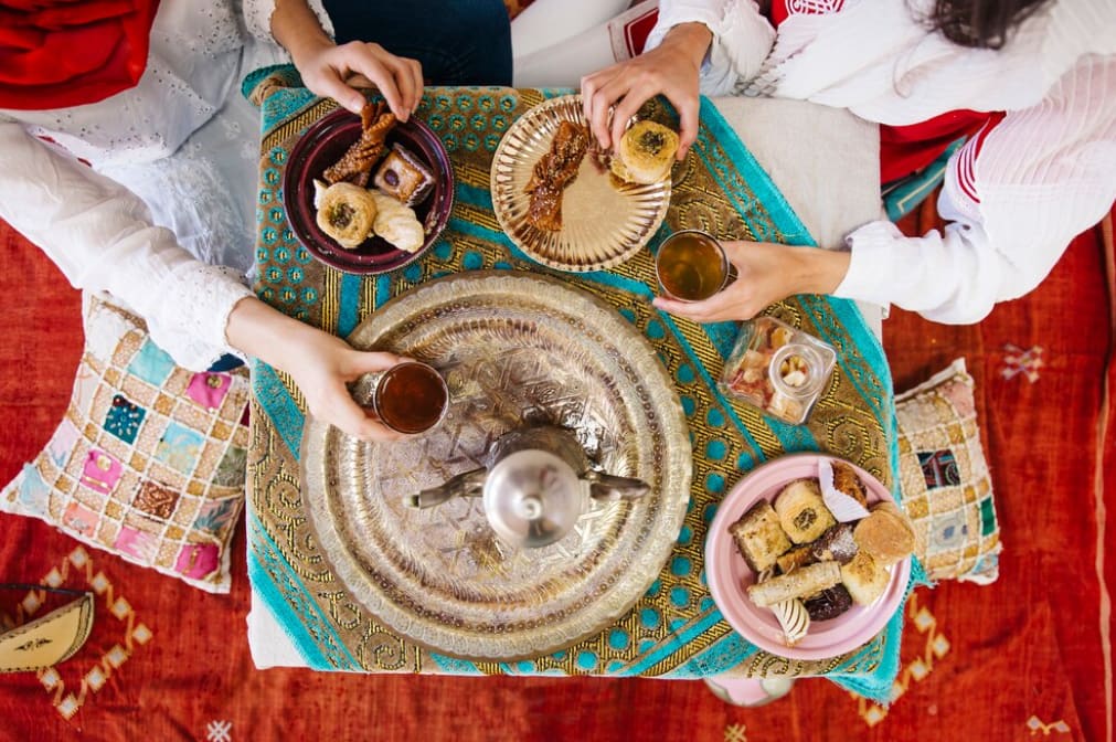 Overhead view of people sharing a traditional Arab meal on a decorated mat.